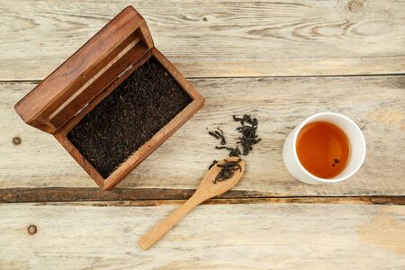 black Indian natural tea in a box, on a spoon and brewed in a glass on a wooden background. the view from the topの写真素材