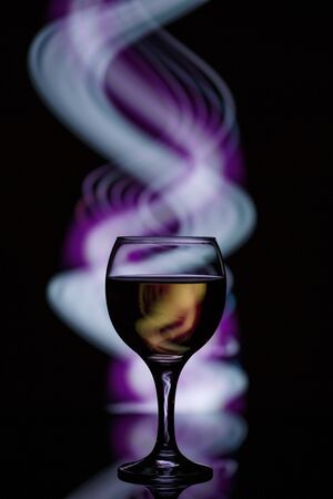 a glass with a drink on a dark beautiful background illuminated with colored light.の写真素材