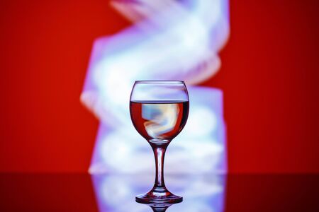a glass with a drink on a beautiful red background illuminated with colored light.の写真素材