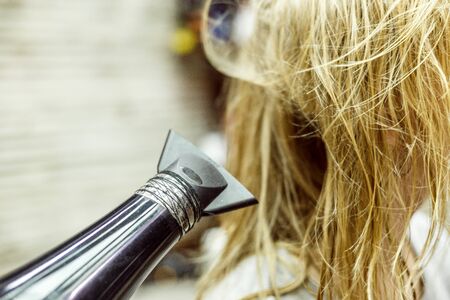 unidentified blonde woman dries wet hair with Hairdryerの写真素材