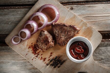 grilled meat with spices and tomato sauce on a worn wooden backgroundの写真素材