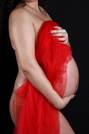 naked pregnant woman shows the changes that have occurred to the body during pregnancy. on black isolated backgroundの写真素材
