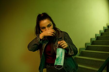 portrait of an Asian young woman in a disposable medical mask. stairwell of the hospital. the girl feels symptoms of infection with the virusの写真素材