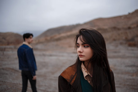 Dramatic portrait of a young brunette girl in cloudy weather. somewhere behind her, out of focus,...