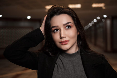 dramatic portrait of a beautiful young woman in a black coat in an underground passage.mosaics on...