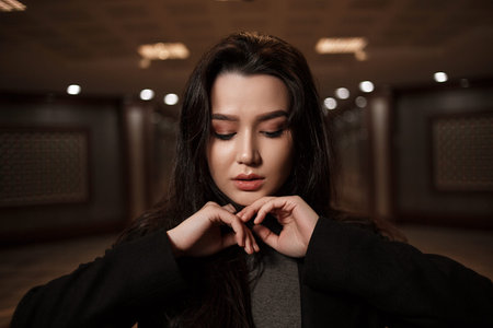 dramatic portrait of a beautiful young woman in a black coat in an underground passage.mosaics on...