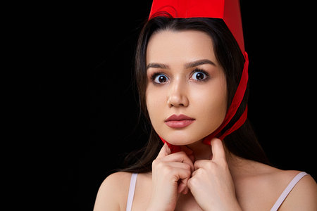a young beautiful woman in white underwear with a red paper shopping bag poses and smiles. on a...
