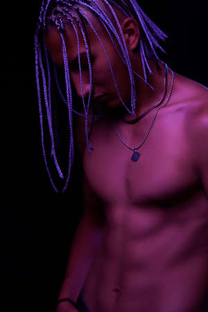 portrait of a young naked african man at studio. High Fashion male model in colorful neon bright lights posing on black background. Art design concept. selective focus.の写真素材