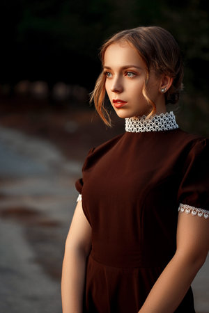close-up portrait of a young beautiful girl in a brown dress in a retro style with a vintage camera...