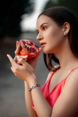 pomegranate in the hands of a young woman. close up. shallow DOF. selective focusの写真素材