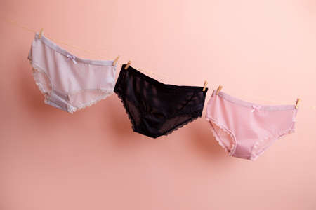 colorful clean women's panties hang on a rope. on a pink isolated background.の写真素材