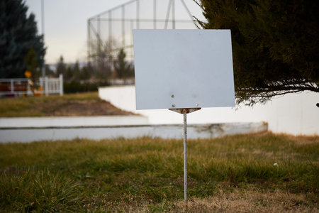 a white sign with a blank space for text on the green lawn.
