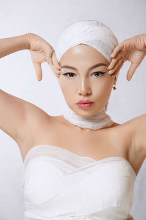 ffashionable portrait of a young beautiful Asian woman in bandages on an isolated background.の写真素材