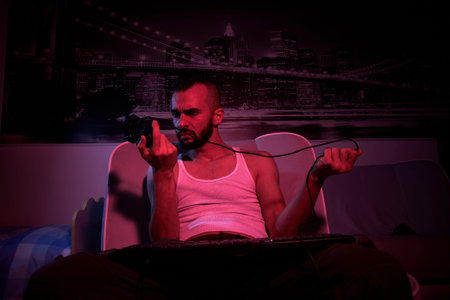 a thirty-year-old guy with a joystick in his hands plays computer games, compares the joysticks,...