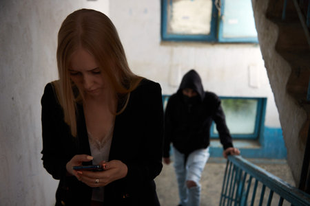 a maniac, a man in a black hood is chasing a young woman on the stairs. the girl is worried, she...
