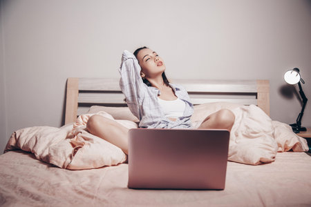 a young Asian webcam model girl is sitting in front of a laptop with her legs spread. she...