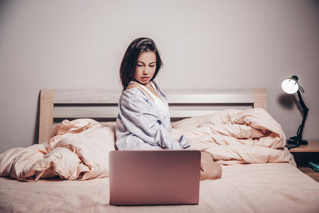 a young Asian webcam model girl is sitting in front of a laptop. she communicates and shows her charms. low depth of focus,artistic photo processingの写真素材
