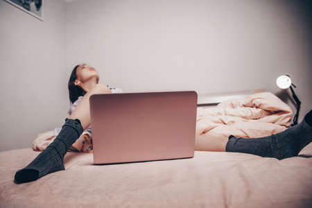 a young Asian webcam model girl is lying in front of a laptop with her legs spread. enjoys and shows her charms. low depth of focus, selective focus.の写真素材