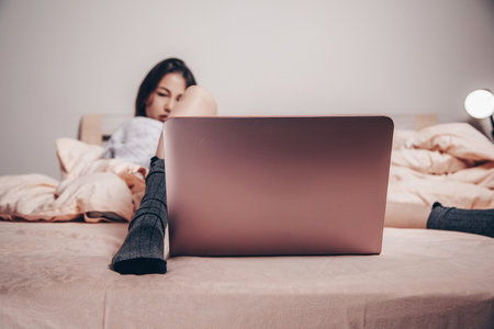 a young Asian webcam model girl is lying in front of a laptop with her legs spread. enjoys and shows her charms. low depth of focus, selective focus.の写真素材