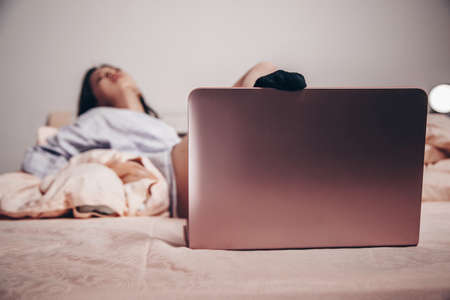 focus on the laptop. at the laptop, a young Asian girl enjoys and shows her charms. low depth of focus, selective focus.の写真素材