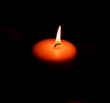 White burning candle on a small dark background.の写真素材