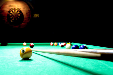 Billiards balls, key and a darts board on the wall