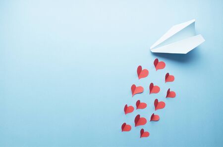 Red paper hearts and a blue paper jet on blue. Love concept.の写真素材