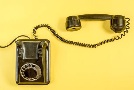 Vintage black landline telephone on yellow background.の写真素材