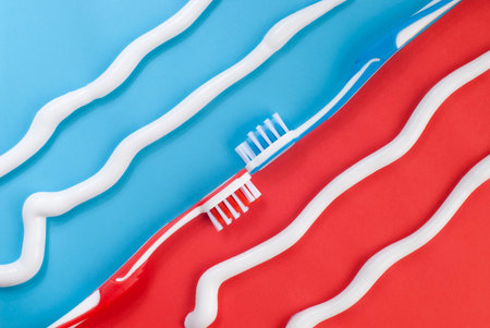 Toothbrushes and curly toothpaste lines on blue and red background