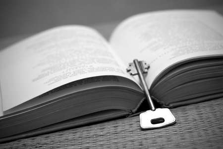 An open book and a key in black and white. Education/wisdom concept with a book and a key.の写真素材