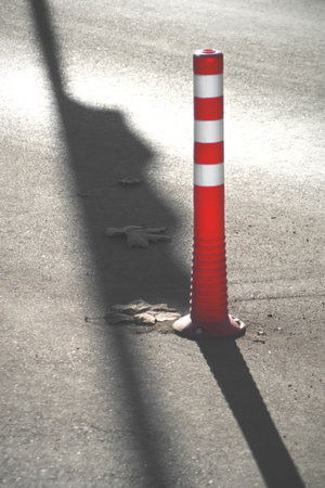 Red and white road cone with strong shadows.の写真素材