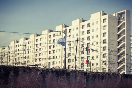 Barbed wire on a grungy wall with a blurry building on the background.の写真素材