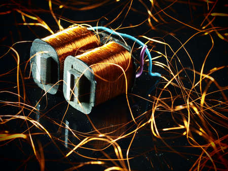 Electricity transformer with unwound copper winding on black backgroundの写真素材