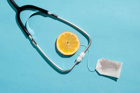 Minimal healthcare concept layout with a traditional stethoscope and lemon tea ingredientsの写真素材