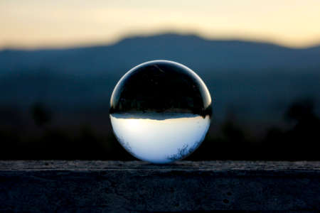 Blurry sinset seen through a lens ball. Lensball with an inverted mountainscape.の写真素材
