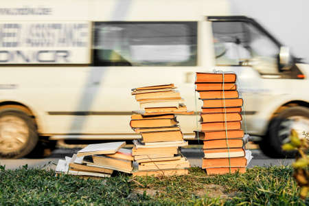 Thrown away bunch of old books lying by the road on the grass.の写真素材