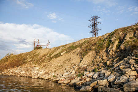 Electricity transmission pylons on the river bank.の写真素材