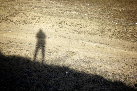 Lonely shadow of a man standing on the hill. Human shadow on the ground.