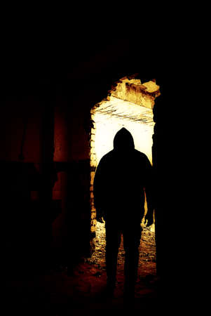 Black human silhouette in a doorway. Human silhouette in an abandoned and ruined place moving to bright light.の写真素材