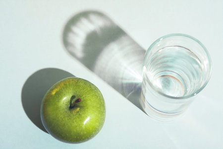 Healthy lifestyle and diet concept with a green apple and a glass of water.