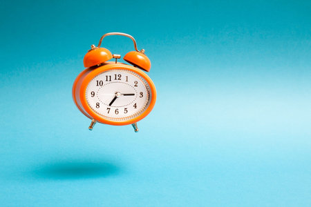 Orange vintage style flying alarm clock. Flying alarm clock on blue background.の写真素材