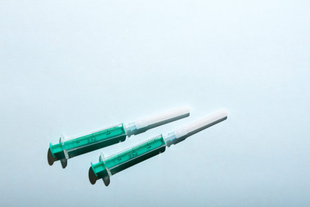 A pair of medical syringes on blue background with free copy paste space for text.の写真素材