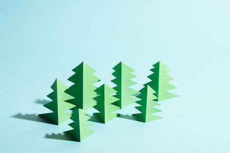 Paper forest with free copy paste space for text. Green paper trees on blue background.