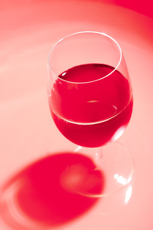 Glass of wine with dark shadow. Wine glass in red monochrome.の写真素材
