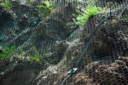 Metal protective net on a hill. Rolling stone protection.