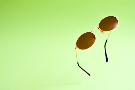 Flying brown golden sunglasses on green background.の写真素材