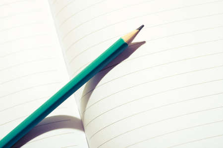 Aqua blue pencil on an open notebook. Close up image of a pencil on white paper.の写真素材