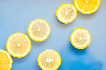 Lemon slices in water on blue background. Swimming lemon slices background.