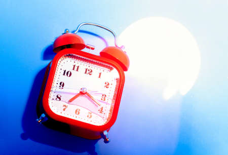 Red retro style analog alarm clock uner the bright light.の写真素材
