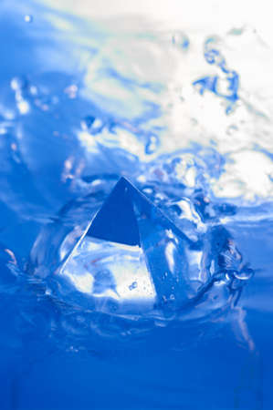 Abstract blue background with water splashen and a geometric object. Pyramid in water.の写真素材